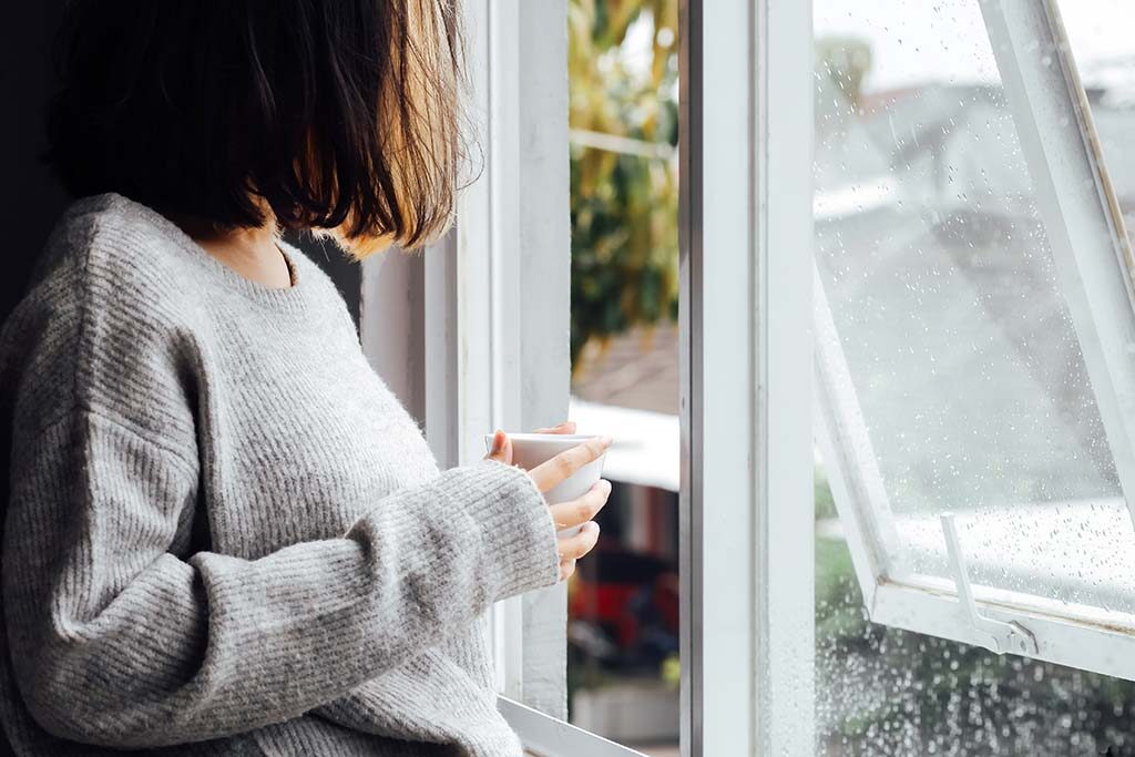 Woman looking out of her home window