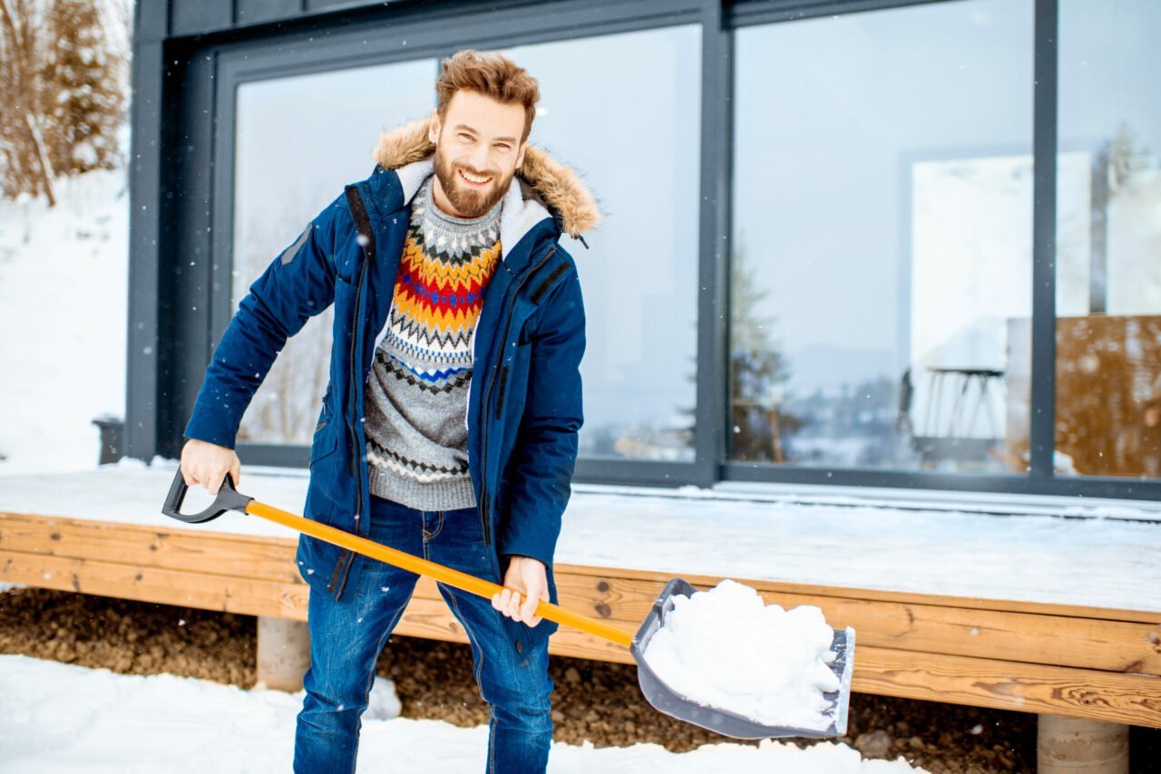man shoveling snow outside of home in the winter